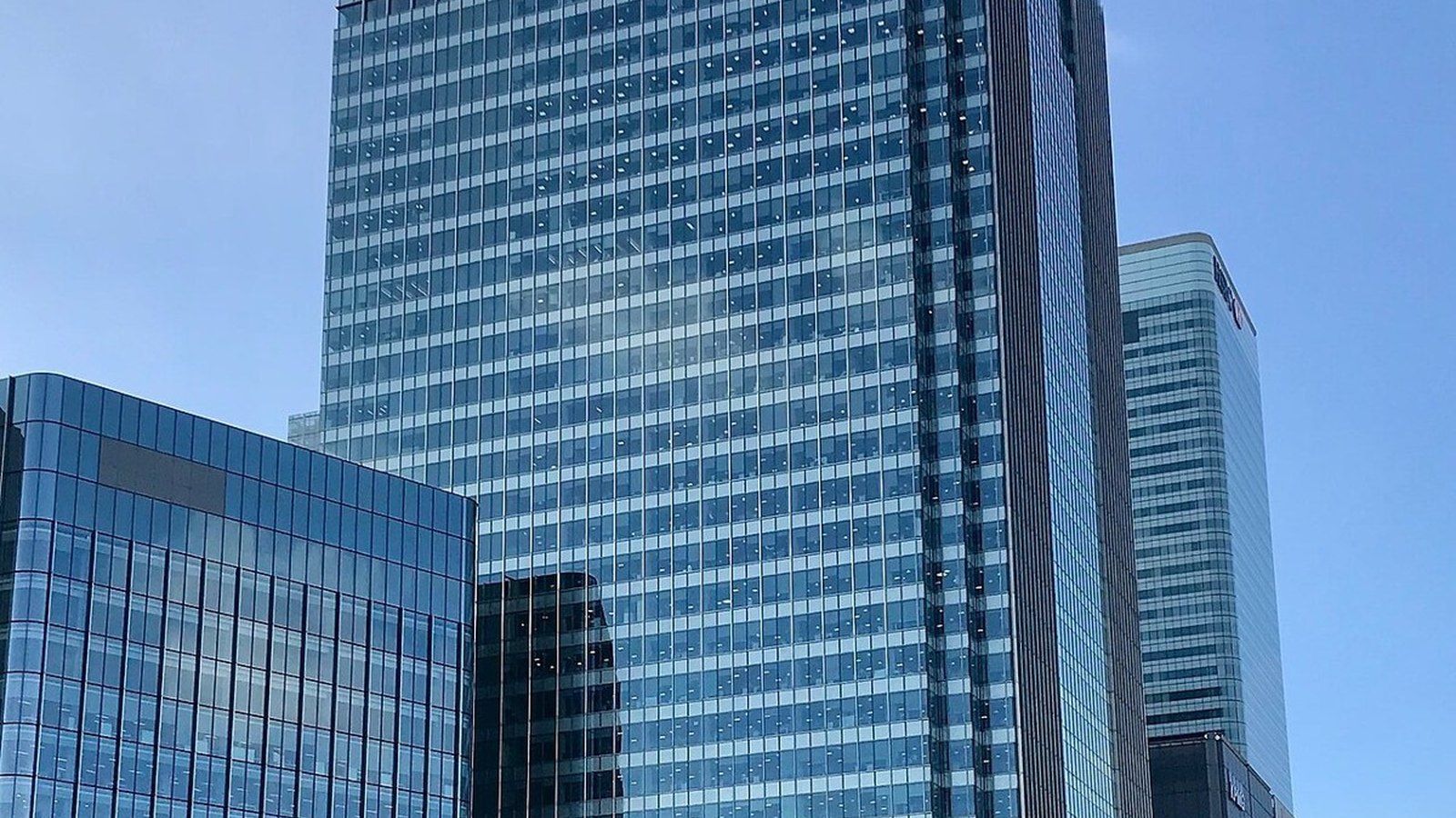 Barclays headquarters tower at One Churchill Place in Canary Wharf, London, rising above dock water