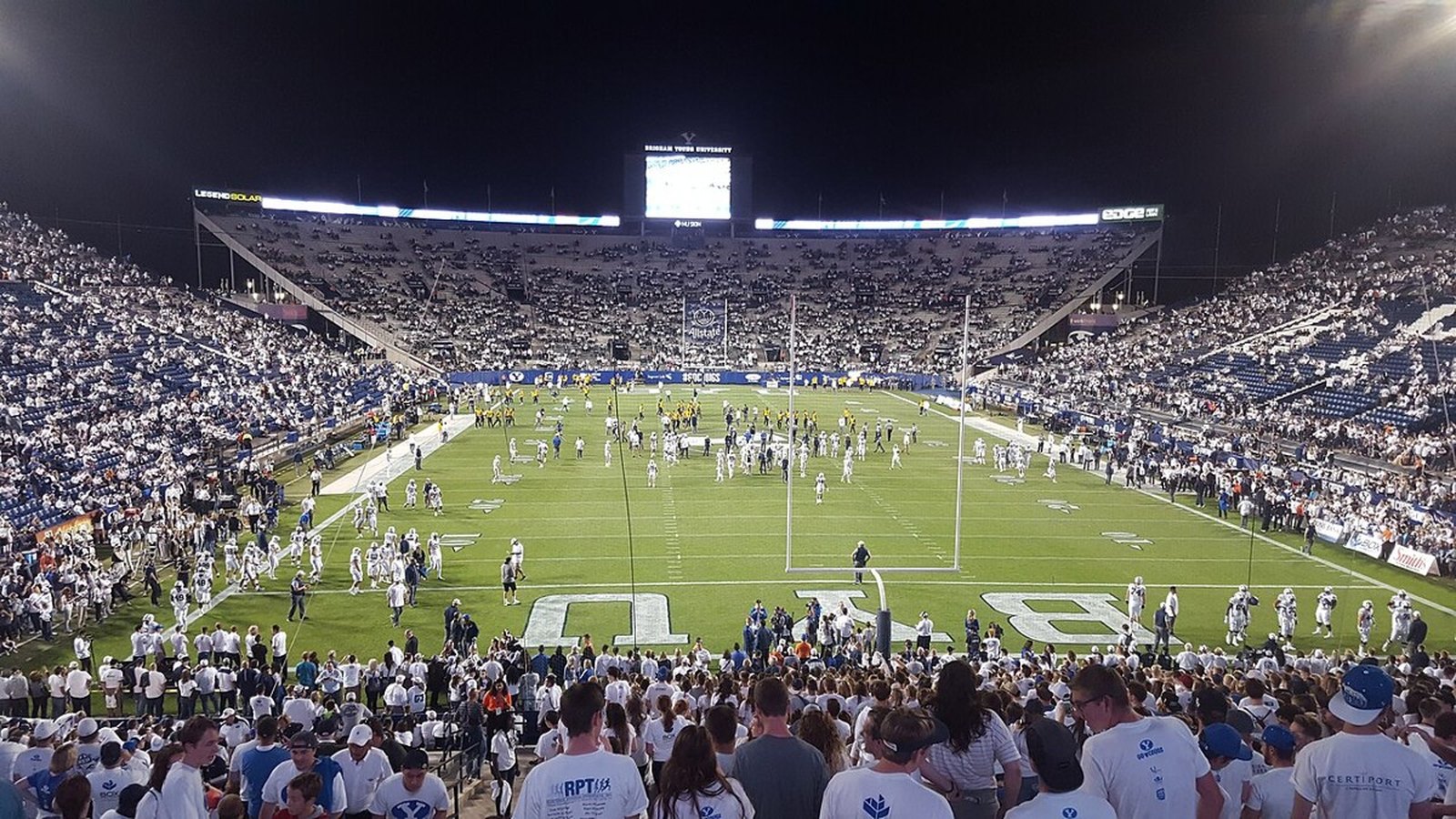 Close-up of a white goal-line pylon and chalk line on the turf of a night-lit college football stadium