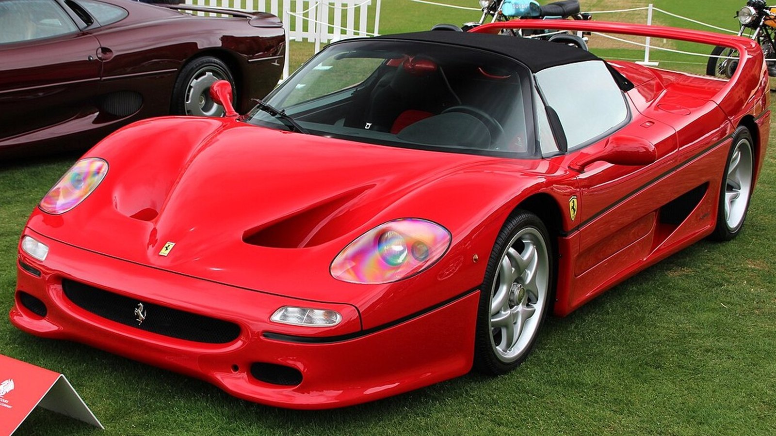 Close-up of a Ferrari supercar's gated manual shifter and black leather interior with red seat inserts