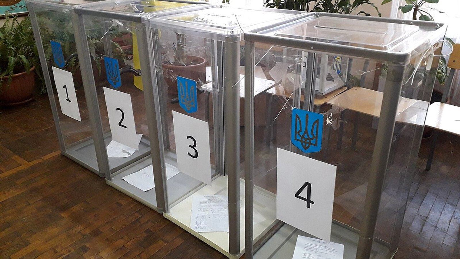 Navy-blue ballot drop box with ivory ballot envelopes at the slot in bright daylight