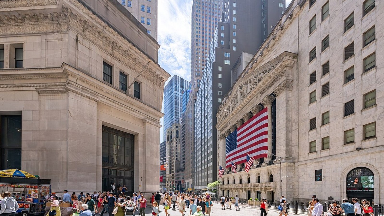 Narrow Wall Street canyon in New York's Financial District with stone bank facades and a street sign in daylight