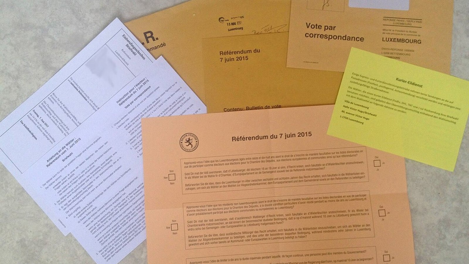 Stack of blank ivory mail-ballot envelopes on a navy counter with a pen beside them