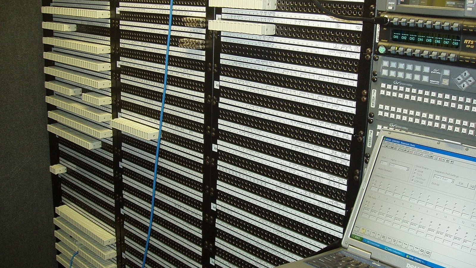 Close-up of a server room patch panel in electric blue and black with one cable pulled loose from its port